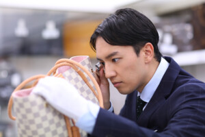 男性鑑定士が、ルイヴィトンバッグを真剣な表情で査定している