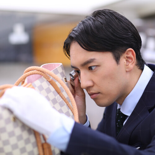 男性鑑定士が、ルイヴィトンバッグを真剣な表情で査定している